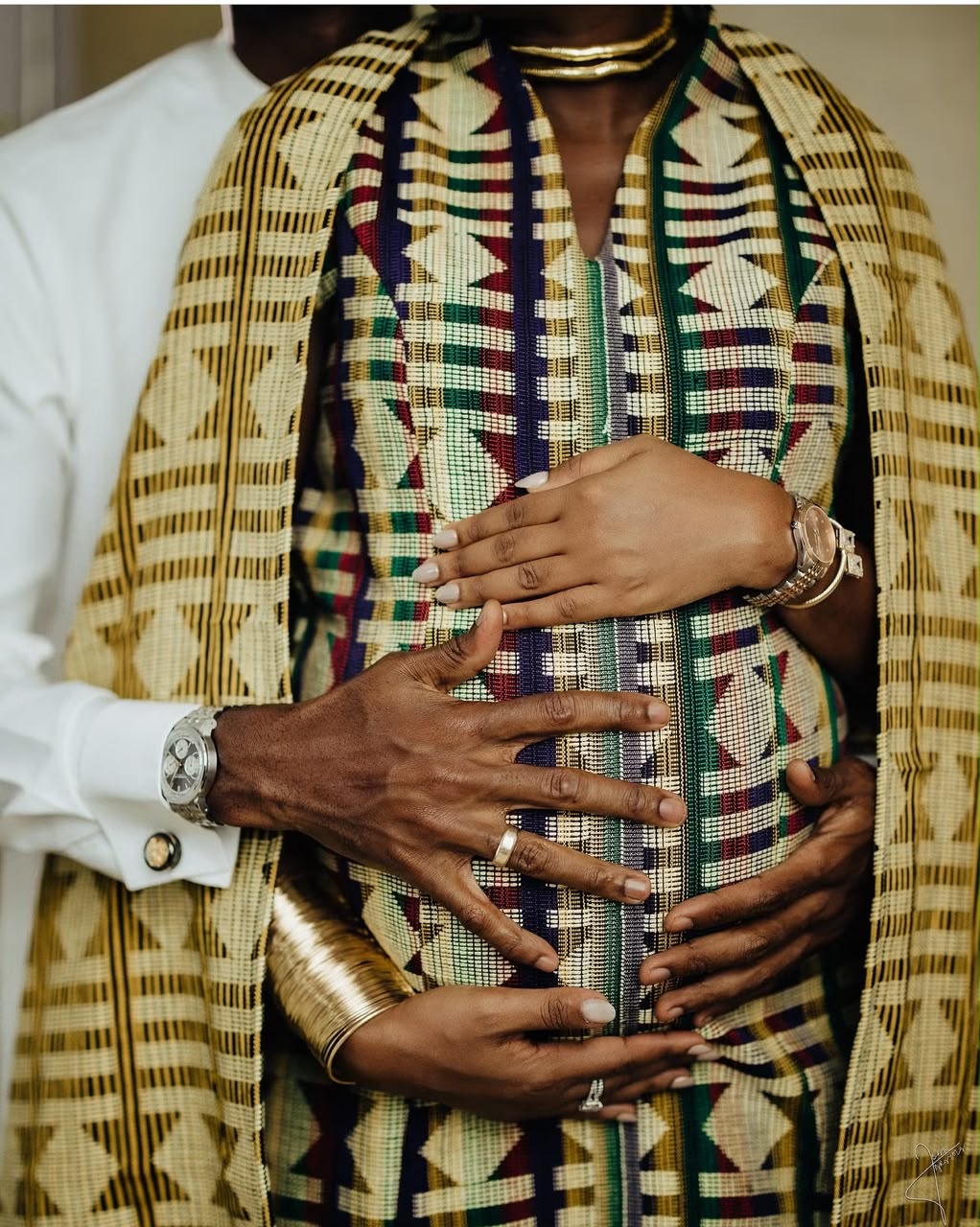 Parents gently cradling a baby bump in patterned traditional attire