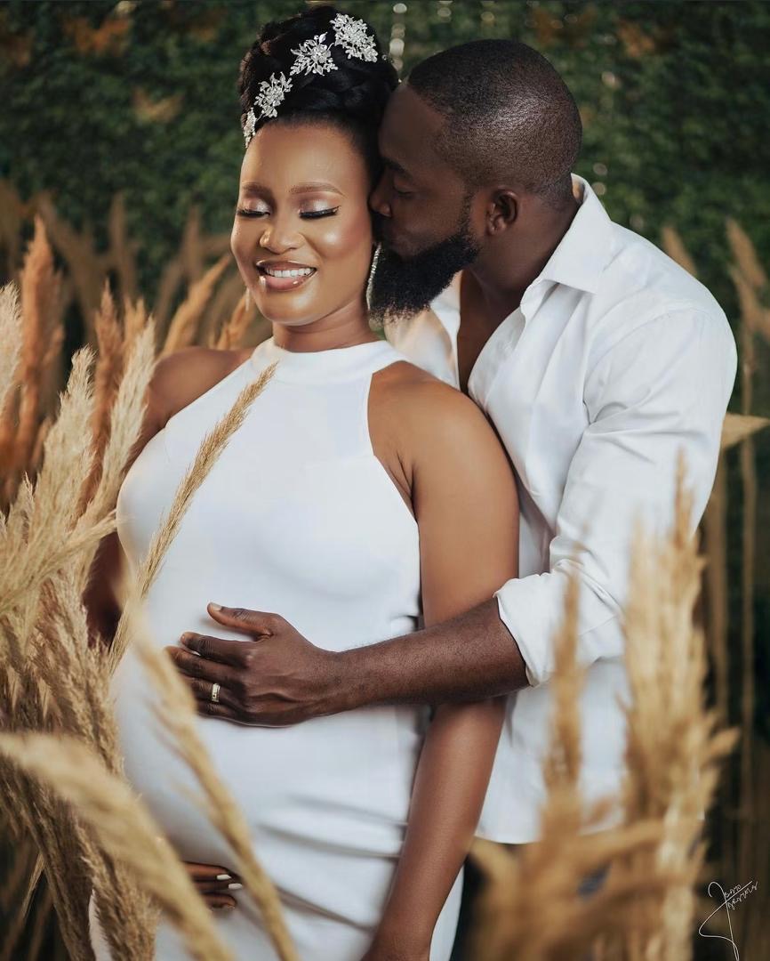 Expectant parents embracing among pampas grass