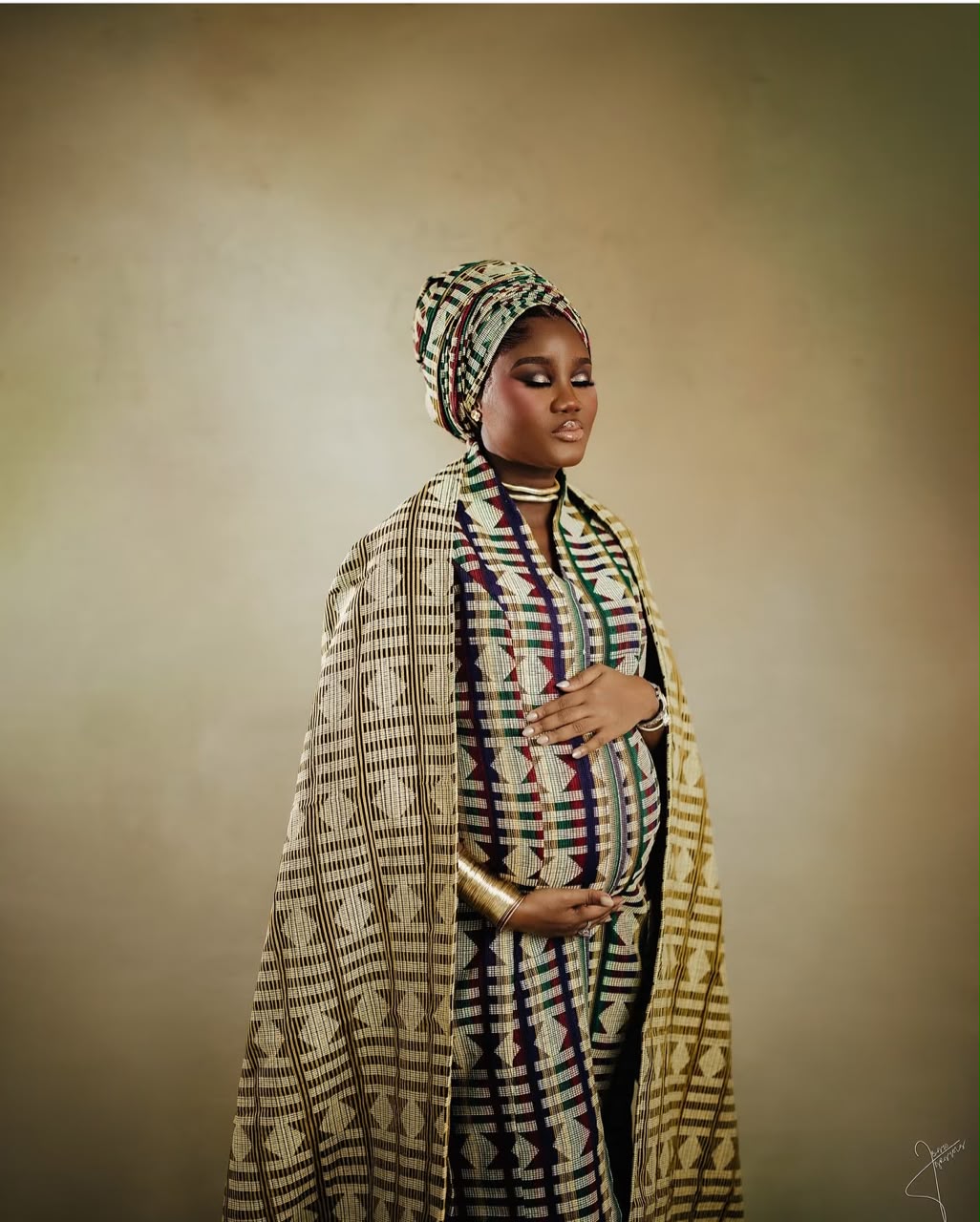 Expectant mother wearing patterned traditional attire and a matching headwrap