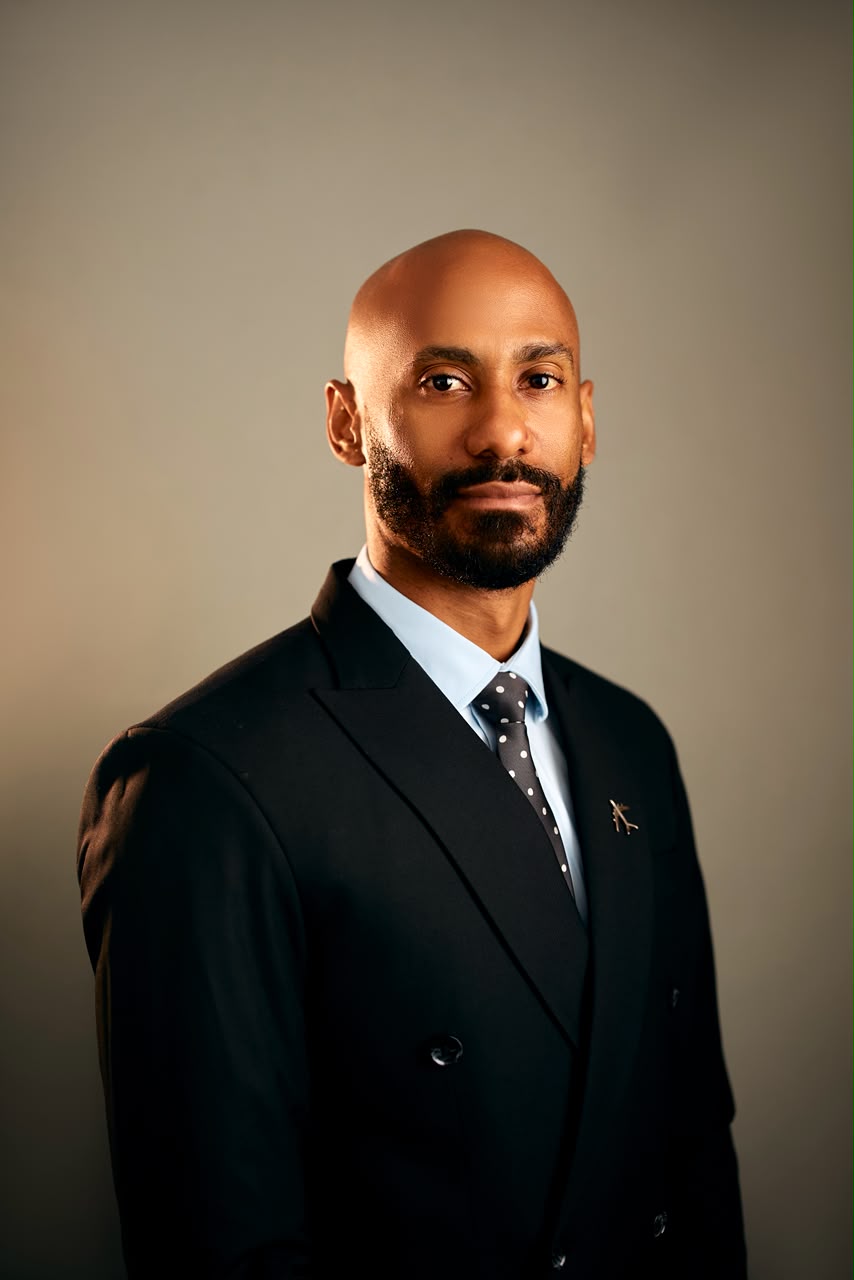 Corporate portrait of a man wearing a black suit and patterned tie
