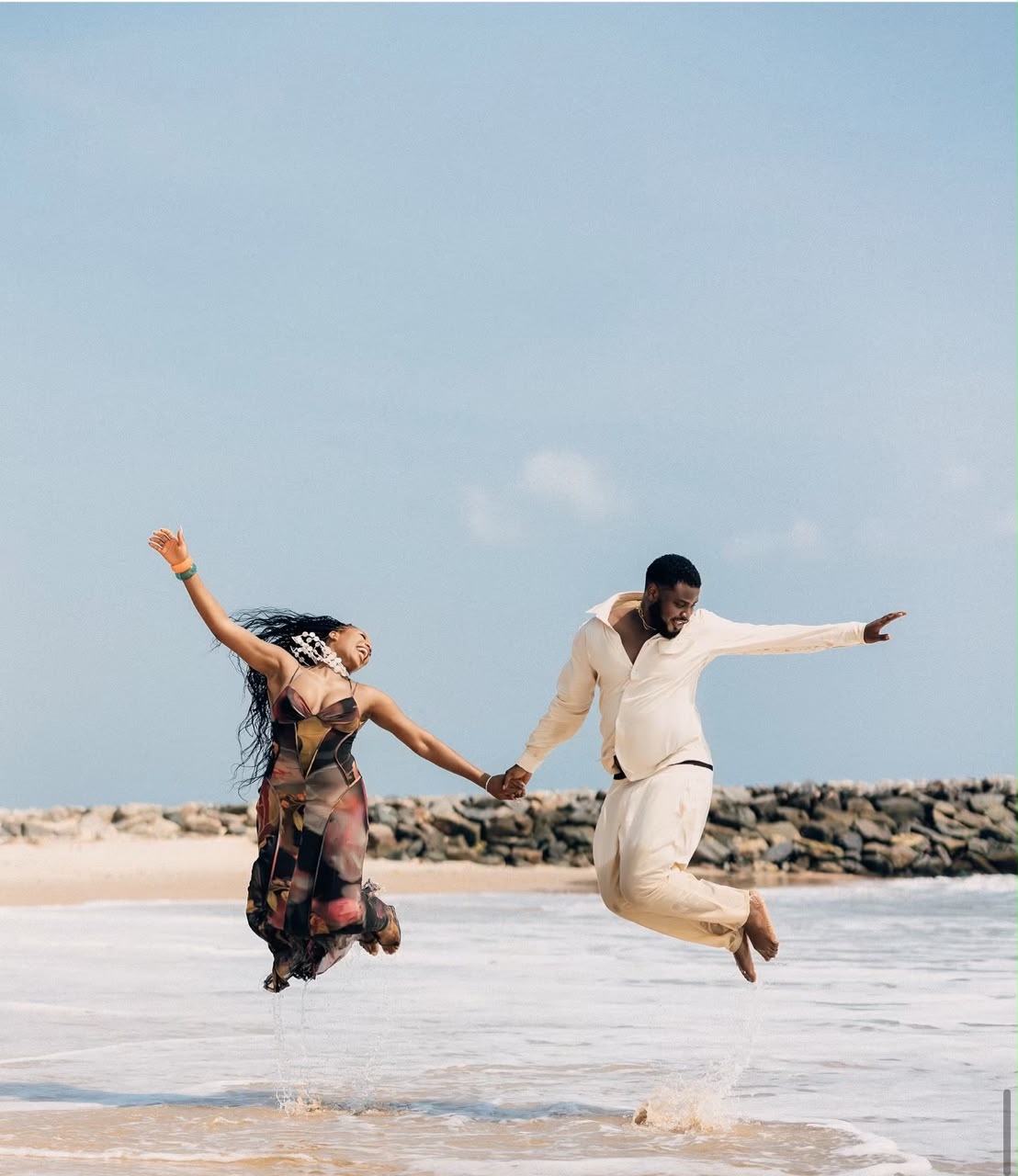 Couple holding hands and jumping together on the beach