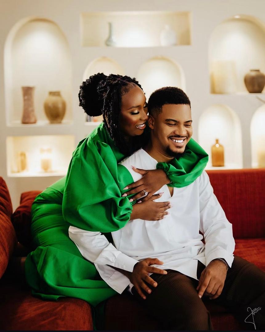 Smiling couple embracing on a sofa, with the woman wearing green
