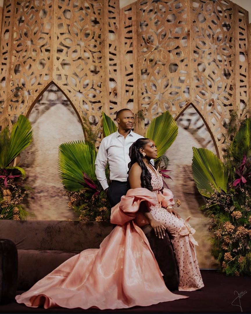 Couple posing beside greenery and ornate wooden screens