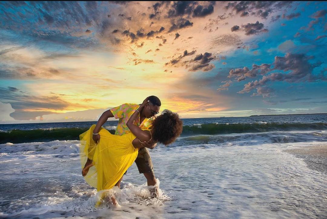 Couple sharing a joyful embrace in the waves at sunset