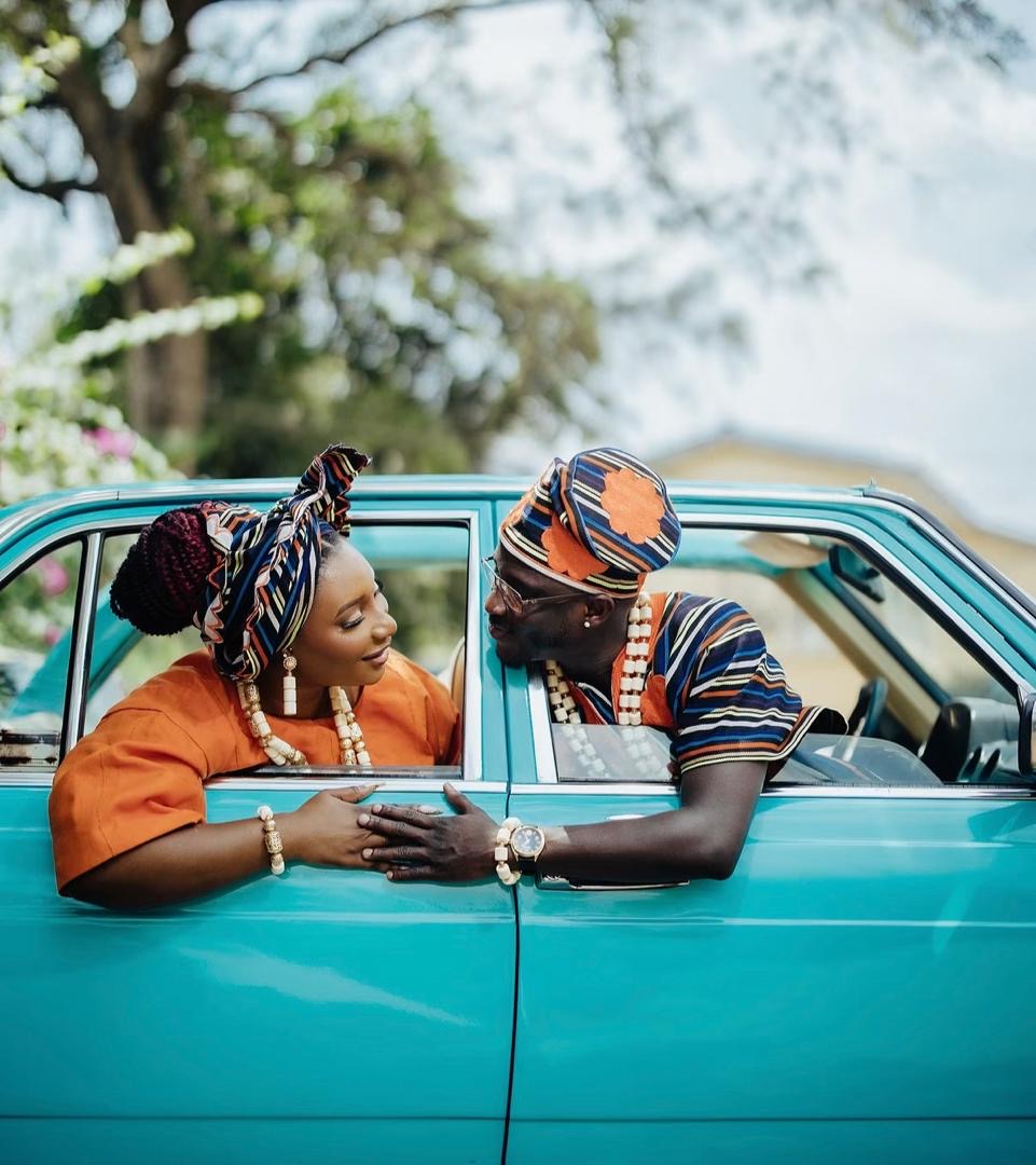 Couple in traditional attire looking at each other through teal car windows