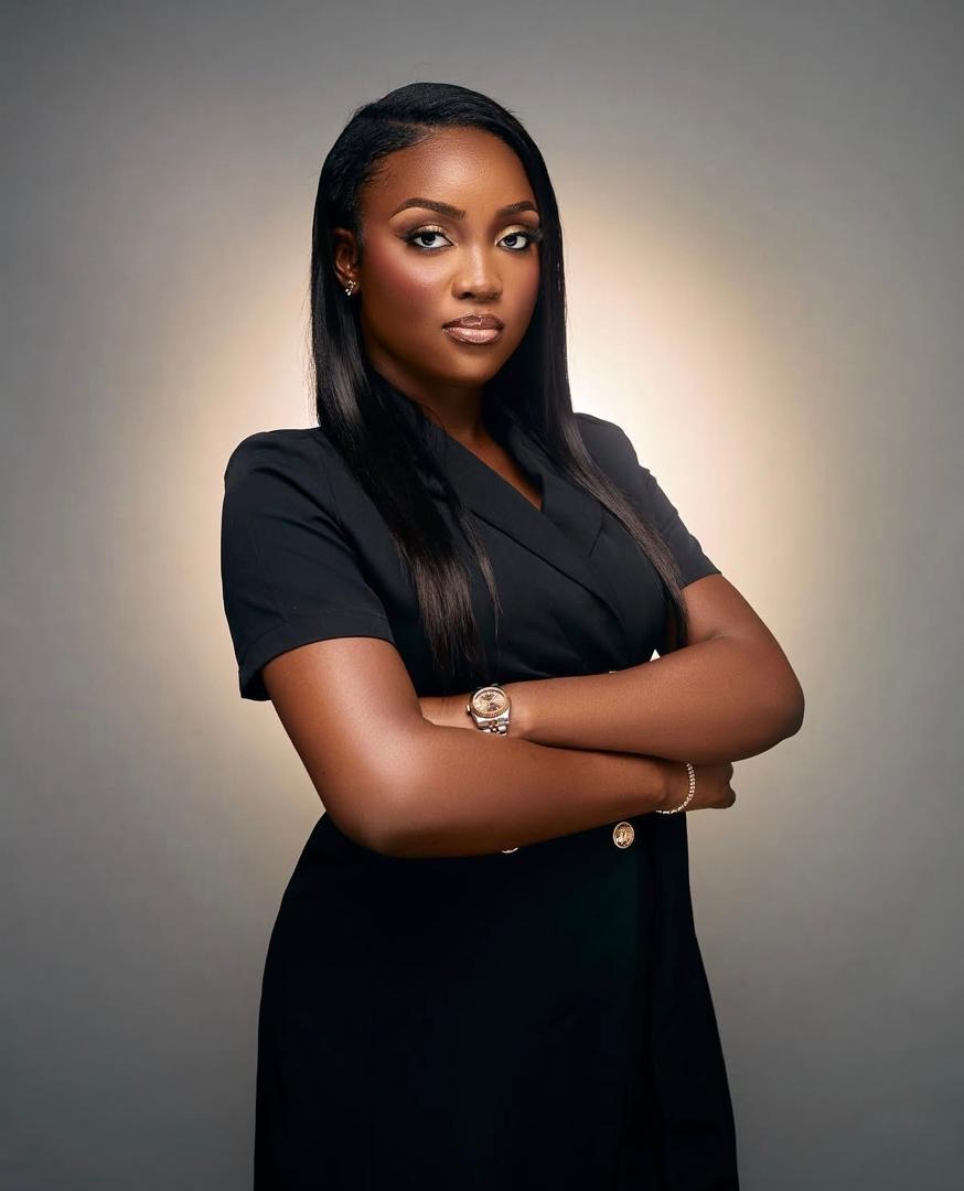 Woman in a black dress with her arms folded against a grey studio background