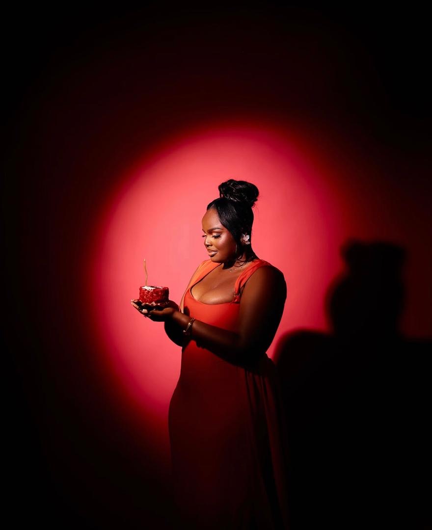 Woman in a red dress holding a small cake under dramatic red lighting