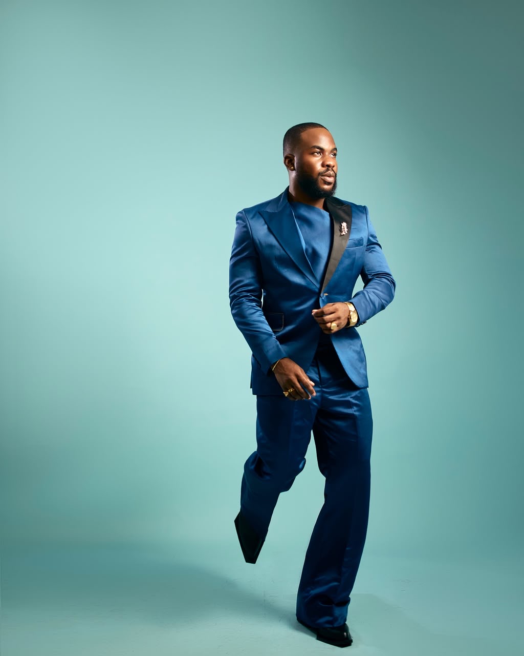 Studio portrait of a man in a blue suit against a teal backdrop