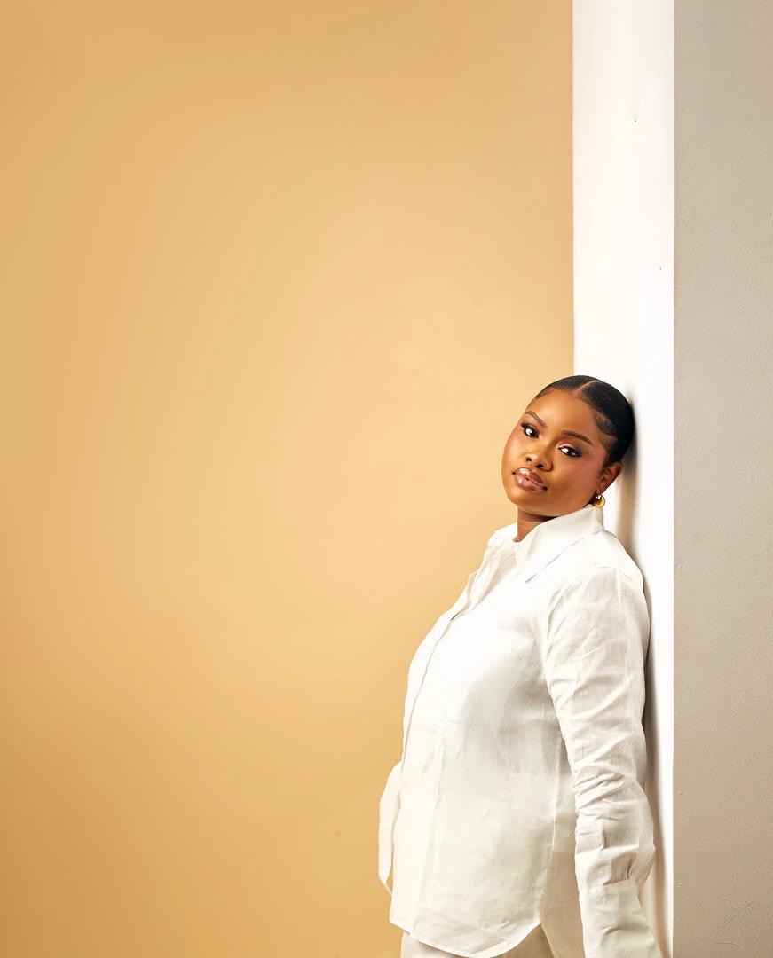 Woman in a white shirt leaning against a wall