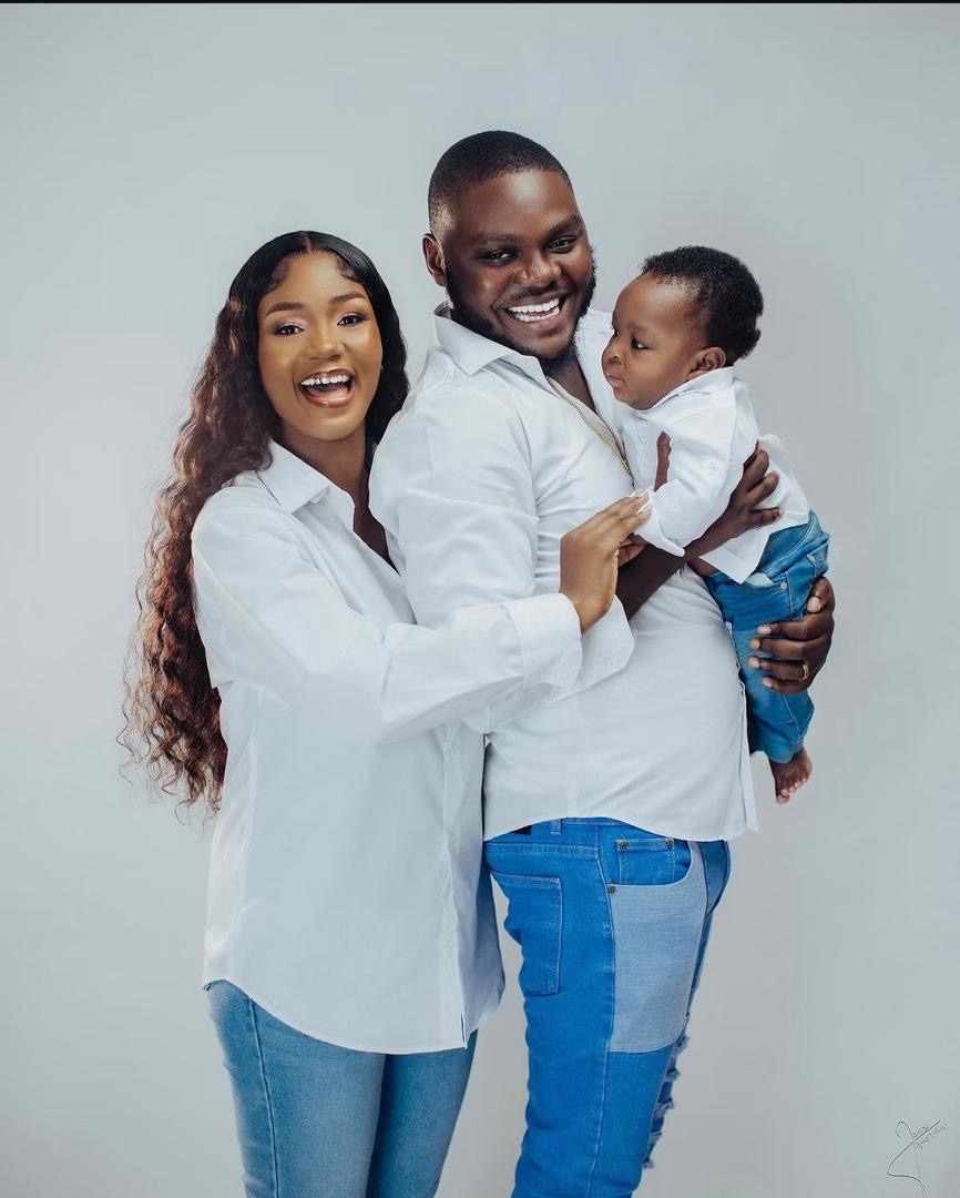 Smiling parents holding their baby in coordinated white shirts and jeans