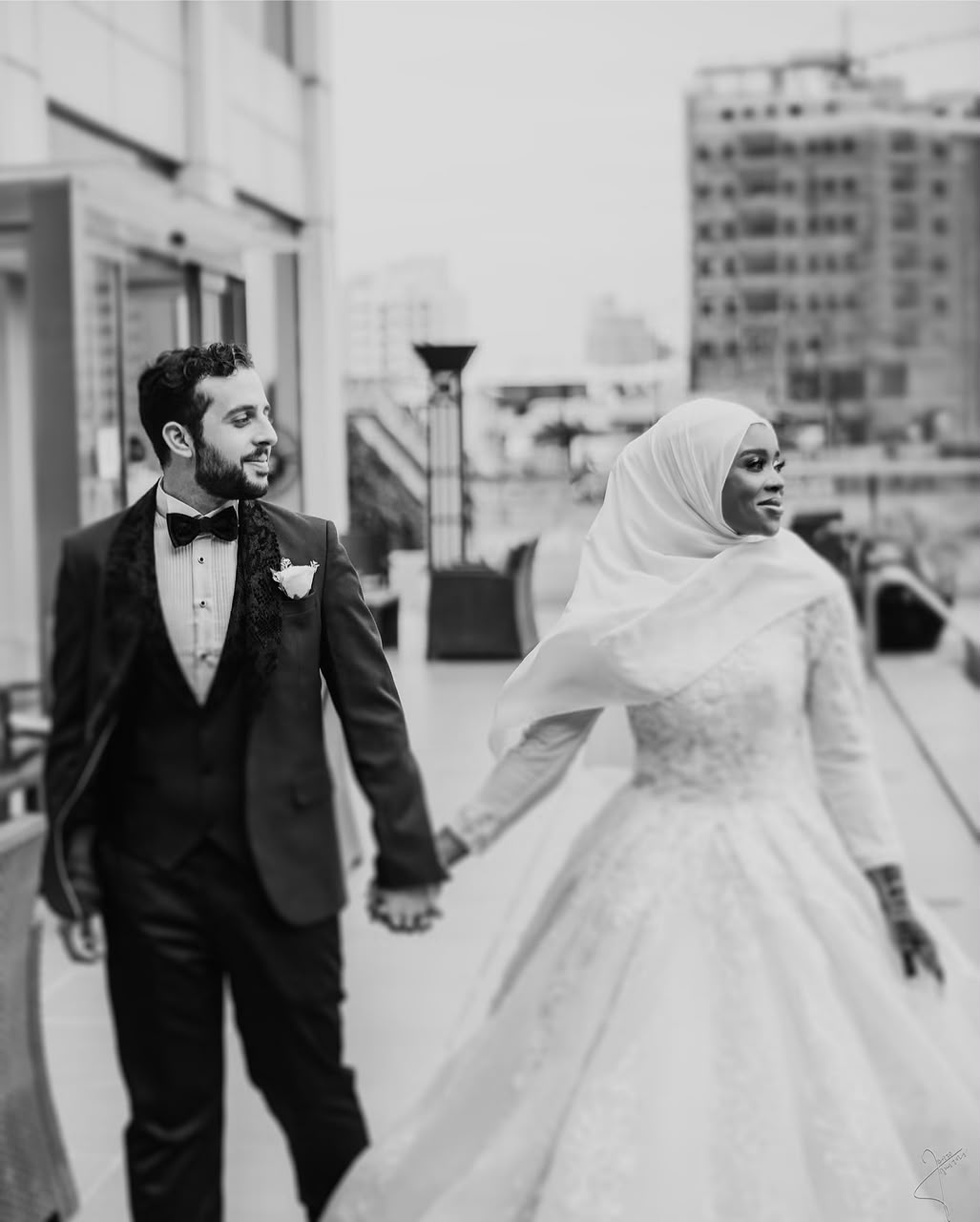 Black and white wedding portrait of a couple holding hands