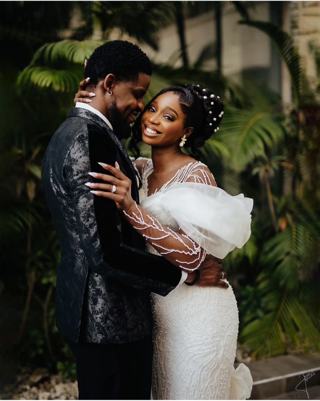 Newlyweds embracing beside green palms