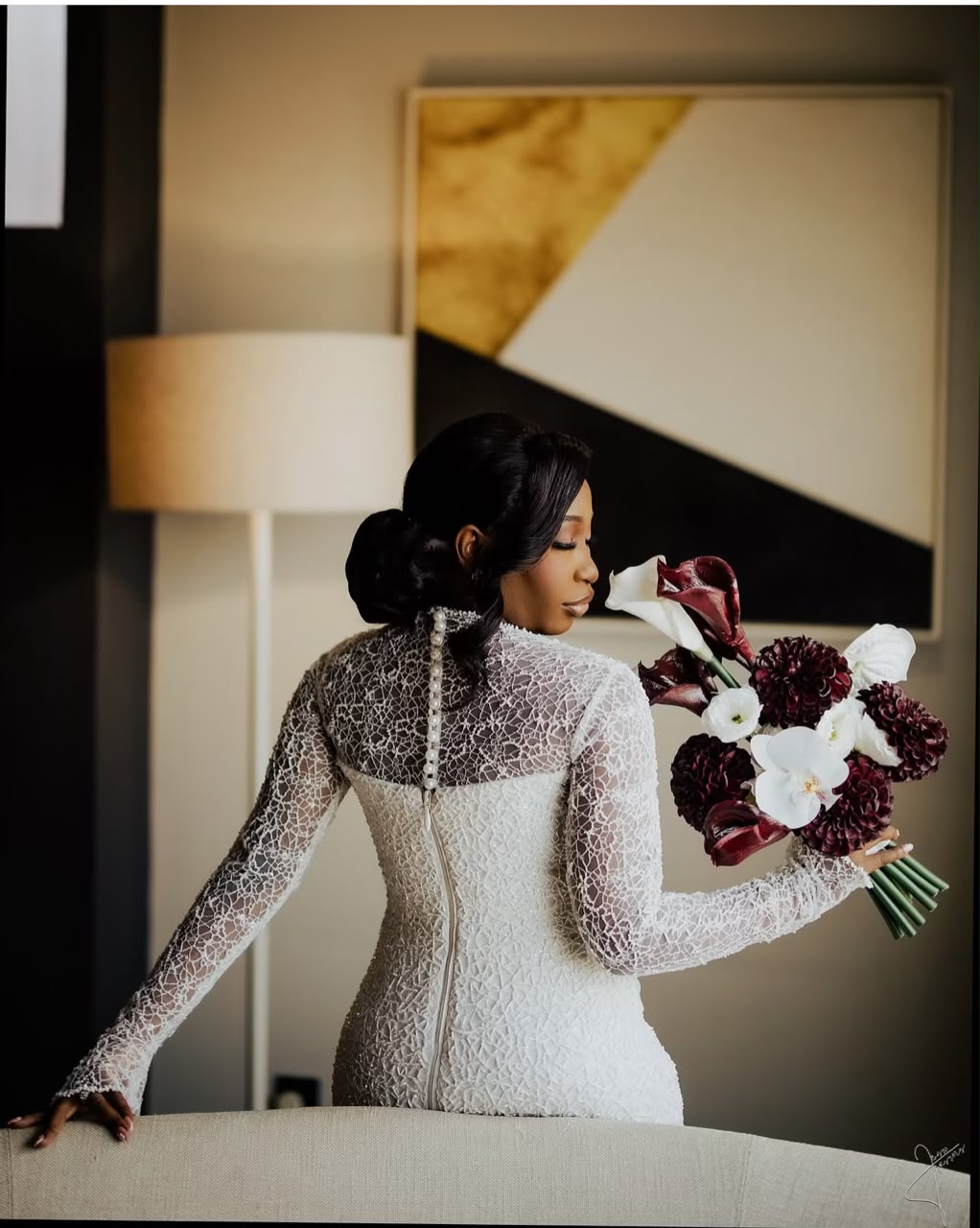 Bride holding a burgundy and white bouquet in a lace wedding dress