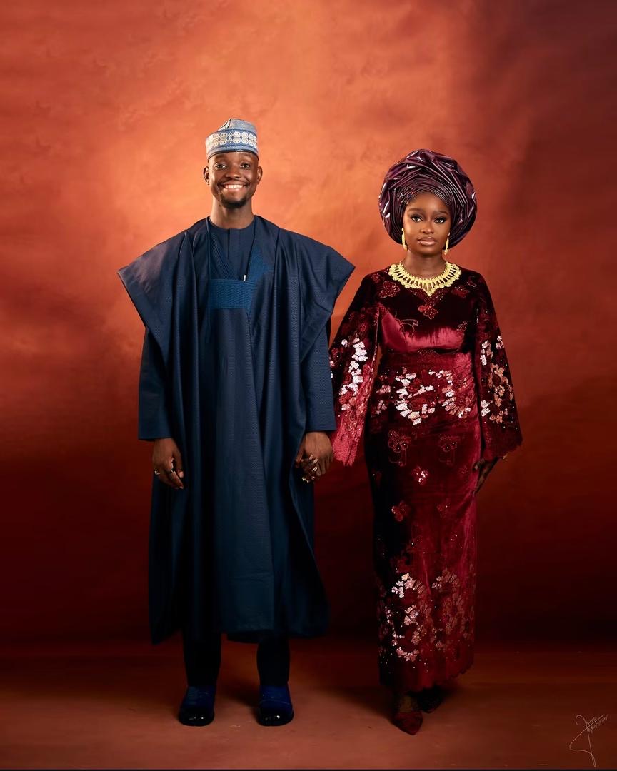 Full length portrait of newlyweds in navy and burgundy traditional attire