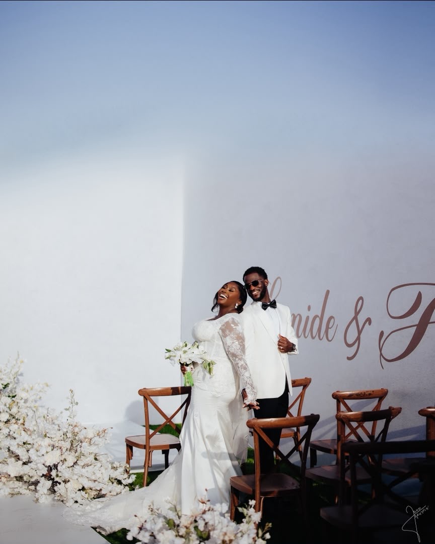 Newlyweds laughing together beside their wedding ceremony seats
