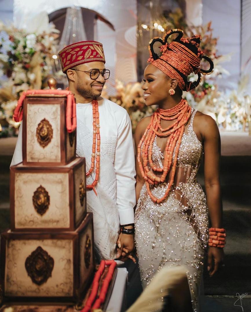 Newlyweds smiling at each other in traditional attire and coral beads