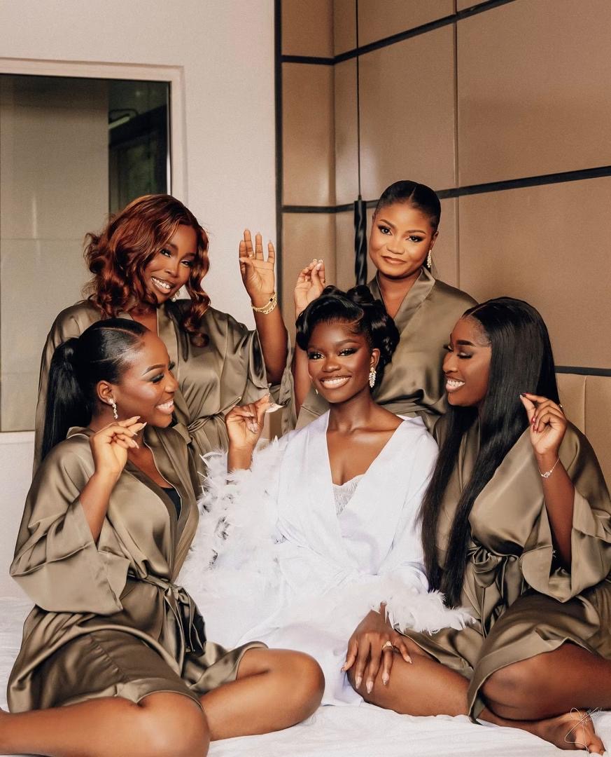 Bride and bridesmaids sharing a joyful moment in satin robes