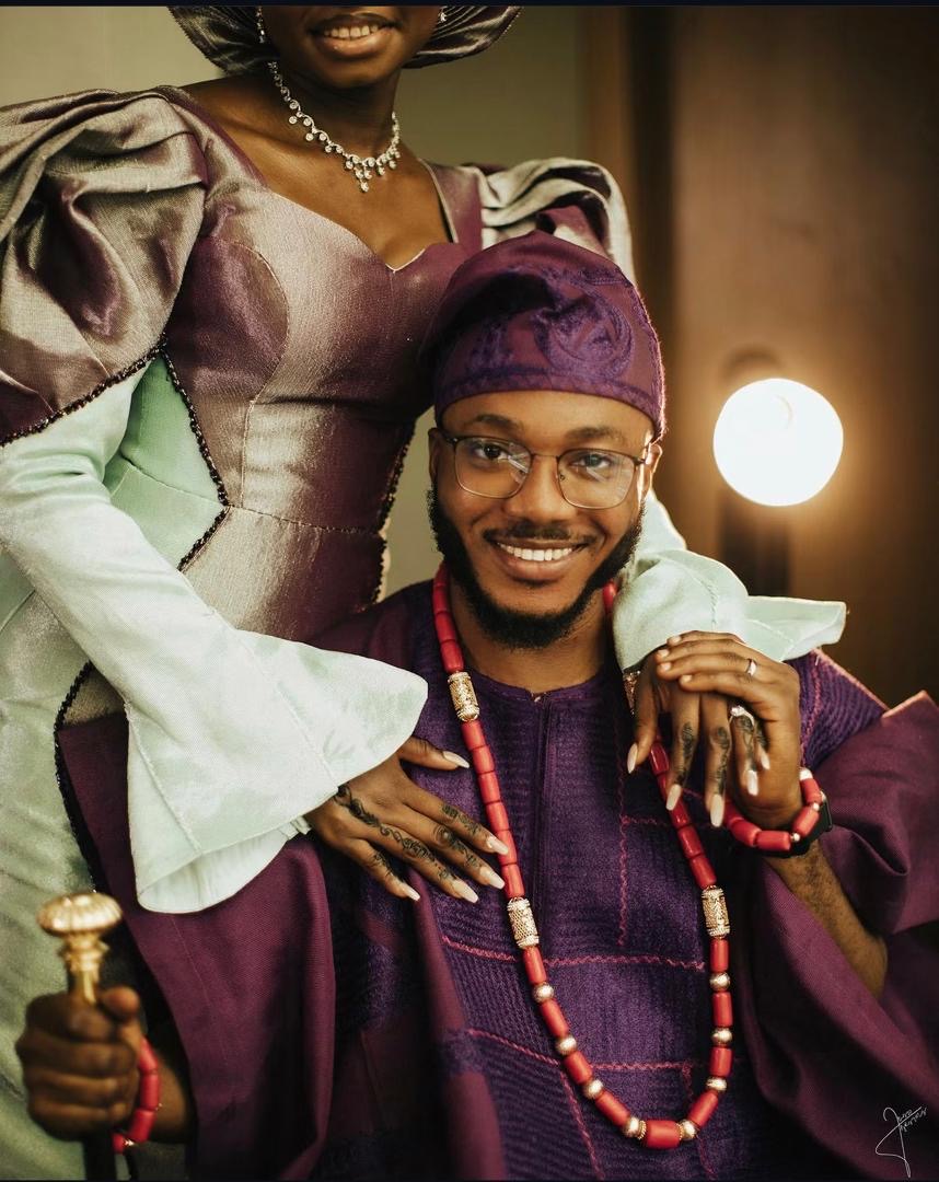 Smiling groom in purple traditional attire with his partner